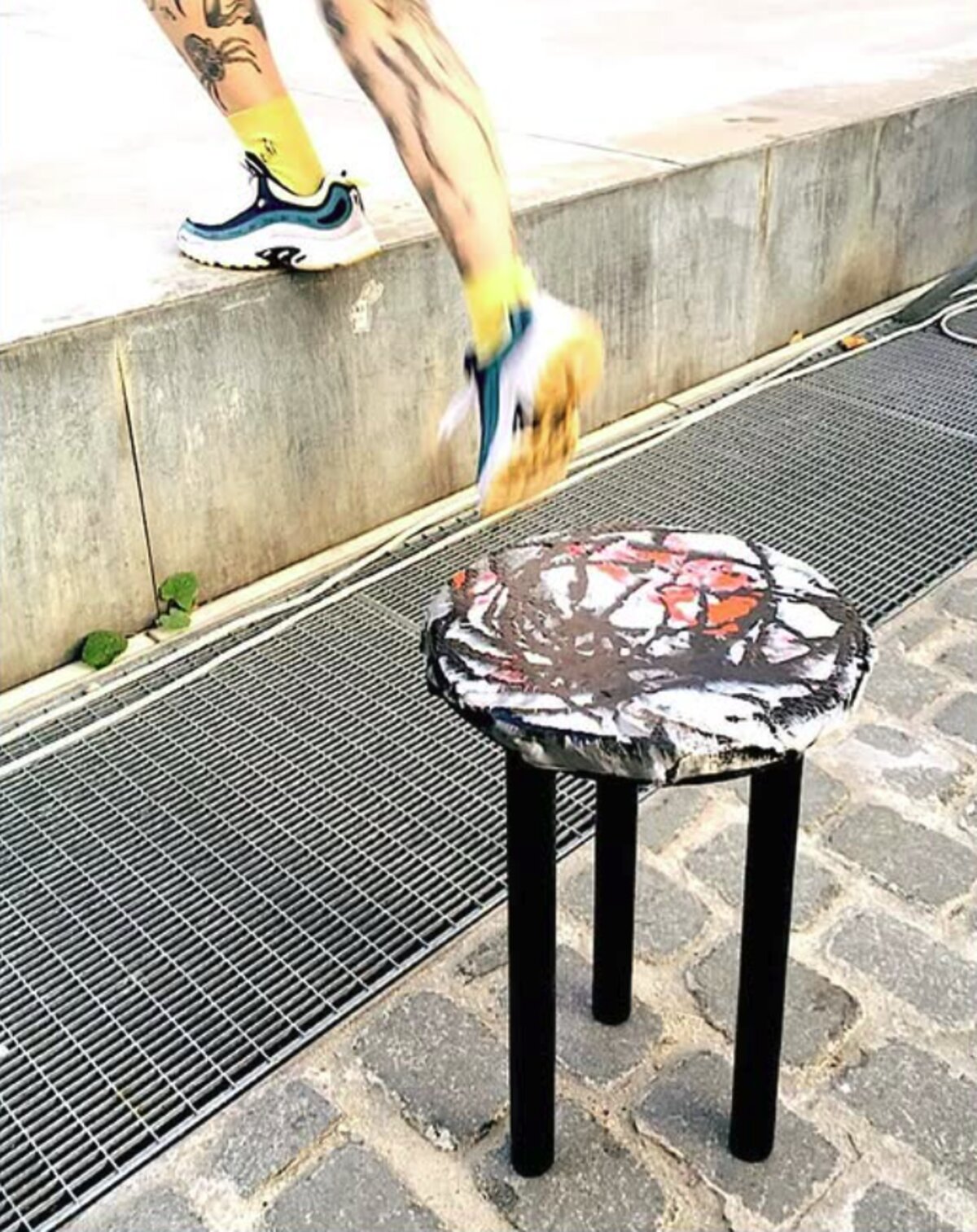 Round recycled-plastic stool on a cobbled street